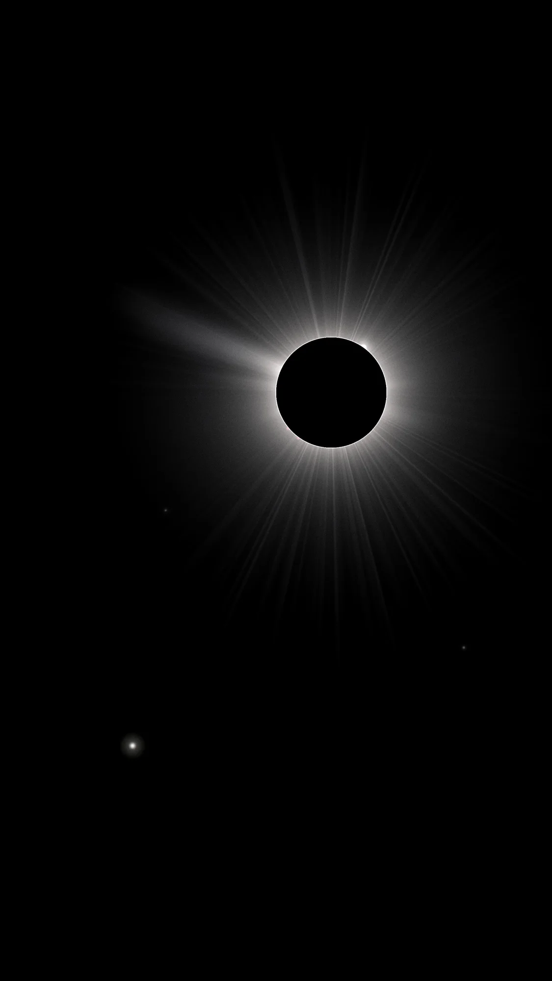 Corona: A total eclipse below the clock: a black moon edged by a white corona with a long streamer, and Venus low in the true-black sky.